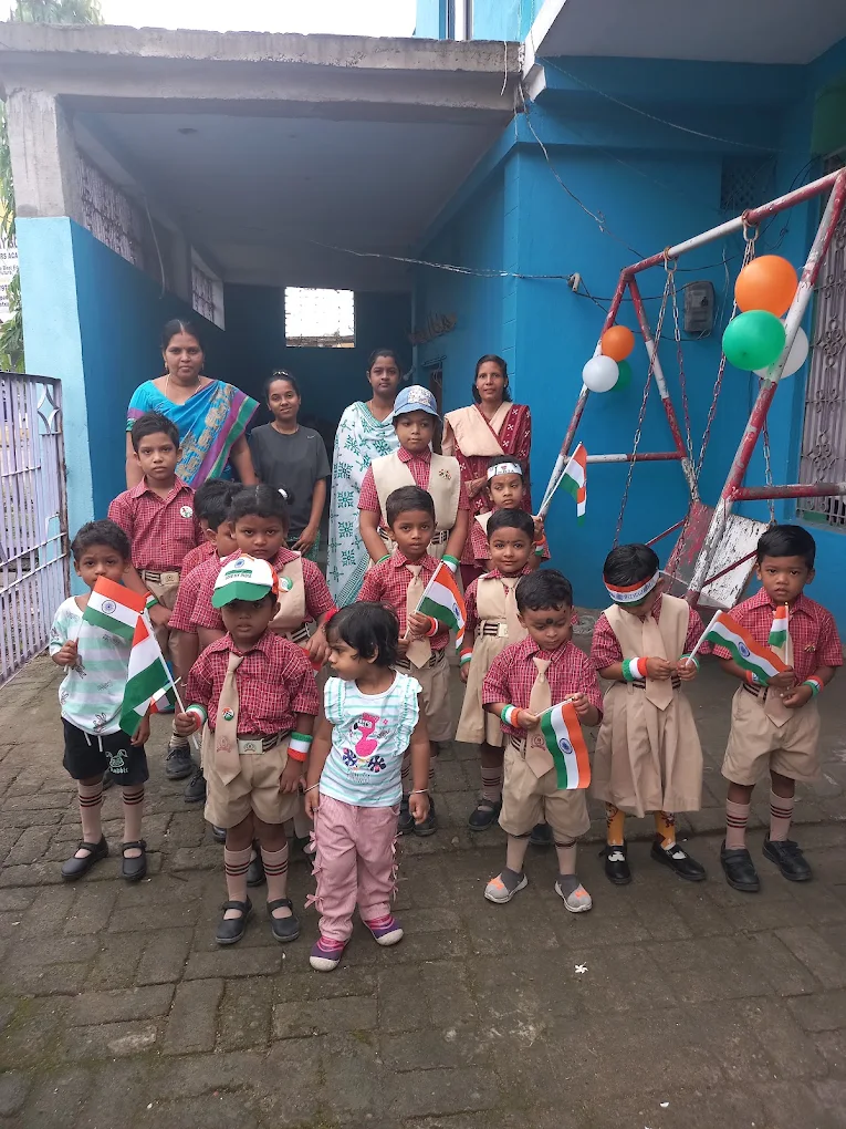 Children holding Indian flags with adults at a school gathering