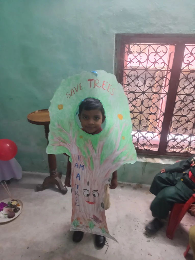 A child wearing a handmade tree costume with a Save Trees message at school