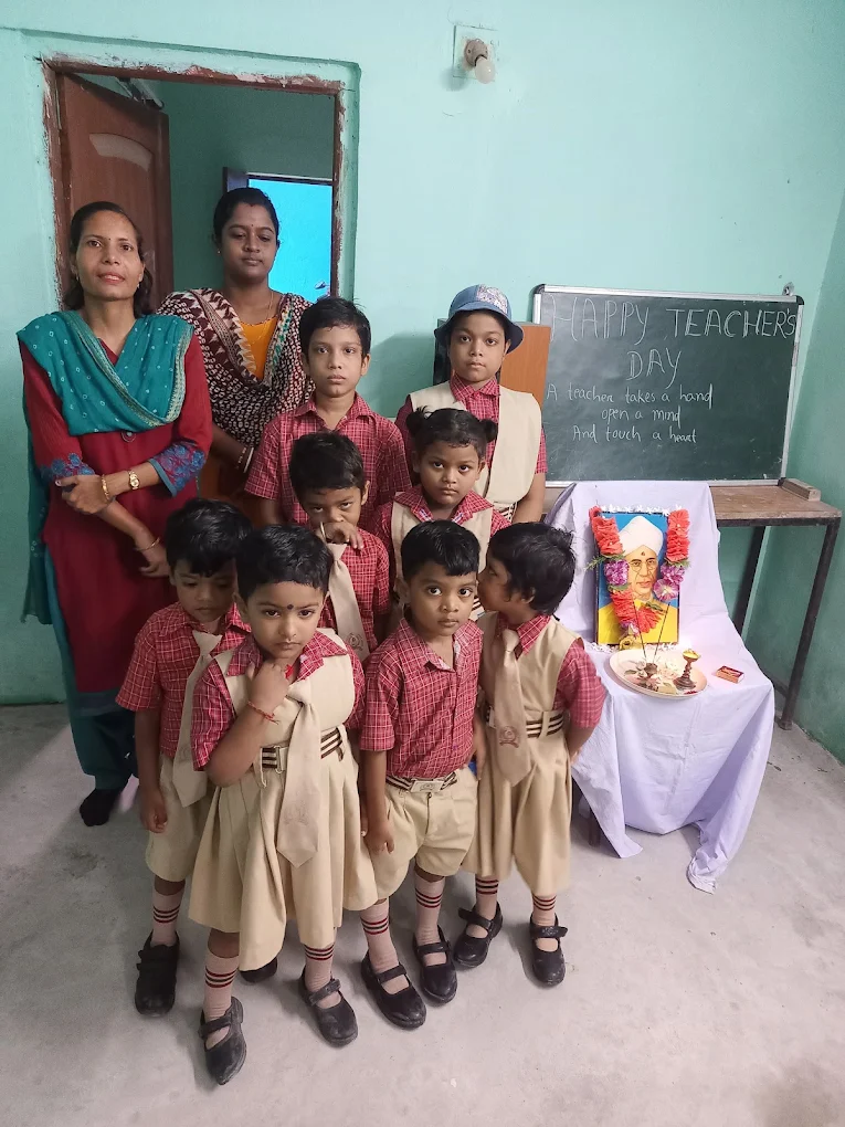 Children and adults gathered beside a Teachers’ Day display at the school